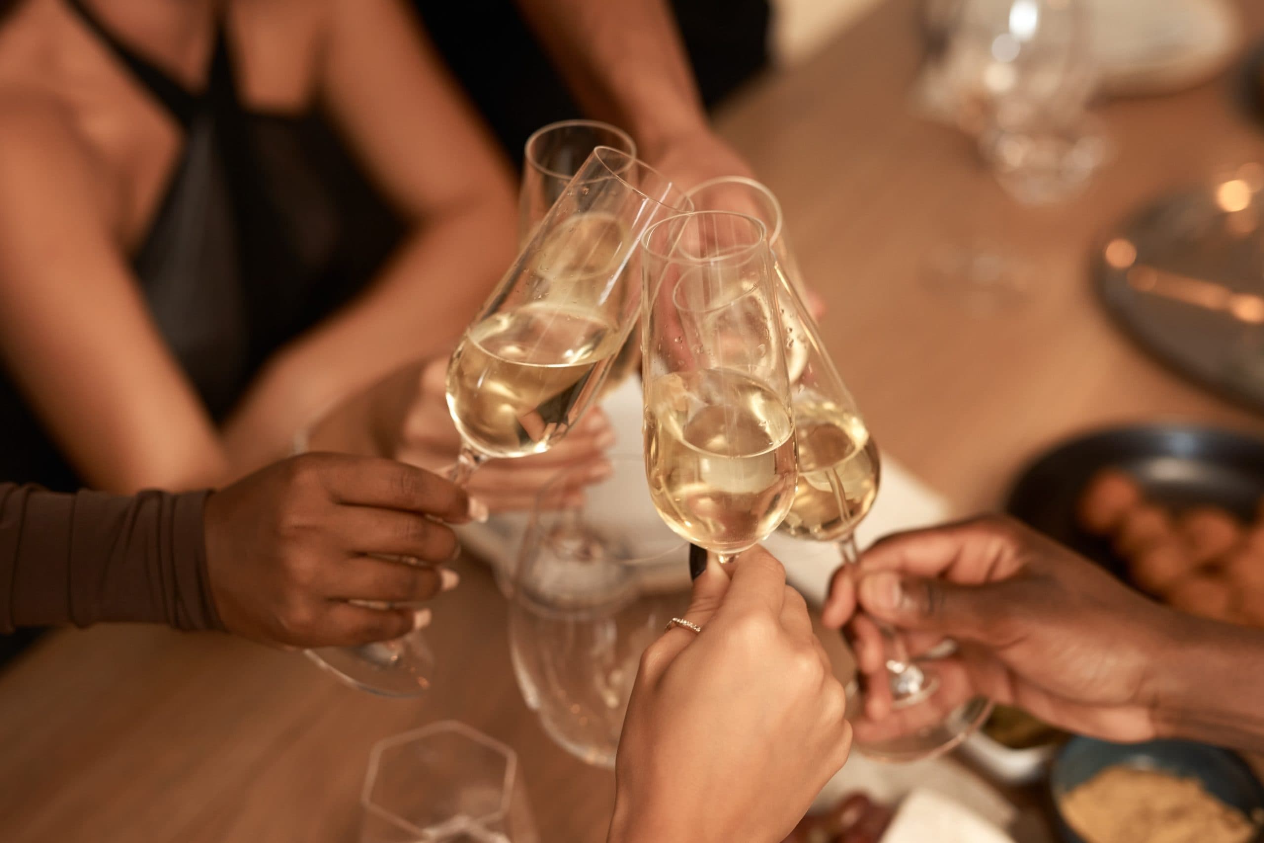 Glada vänner som skålar med vinglas runt ett bord i en varm och inbjudande miljö.